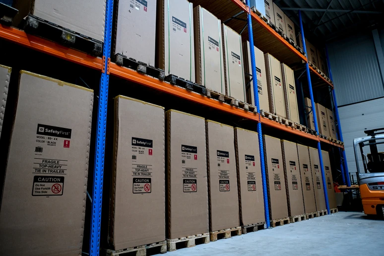 Crated SafetyFirst cabinets stacked two high on warehouse racking, a forklift alongside